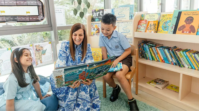 A teacher reads a picture book with a young student in the library