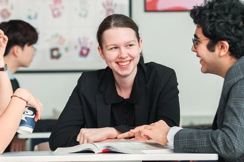 A Senior School student smiles across a desk during a lesson
